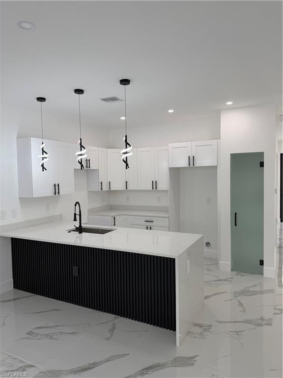 Modern kitchen featuring a waterfall island with a black fluted panel base, white shaker cabinetry, quartz countertops, and three contemporary pendant lights