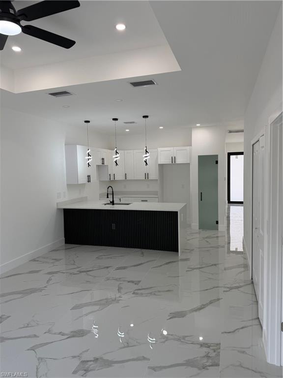 Open-concept living area featuring large format polished tile flooring, a kitchen island with a fluted black base and white countertop, white shaker cabinetry, and contemporary pendant lighting