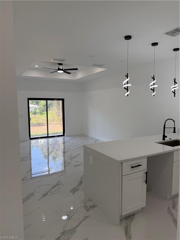 Open-concept living space featuring high ceilings, contemporary pendant lighting, a kitchen island with stone countertops, and large format tile flooring