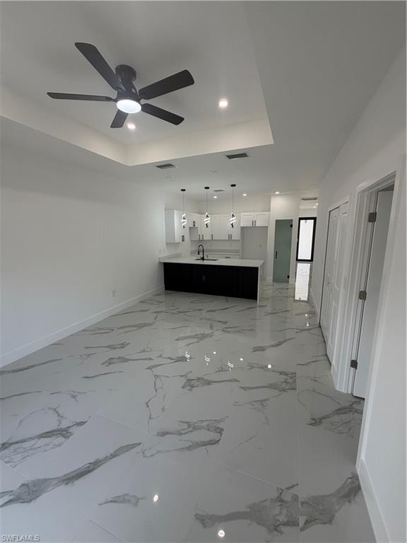 Open-concept living space featuring high ceilings with a modern ceiling fan, recessed lighting, and large format marble-look tile flooring