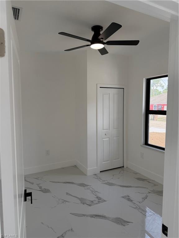 Room featuring white walls, a black ceiling fan with integrated lighting, and a window with black trim
