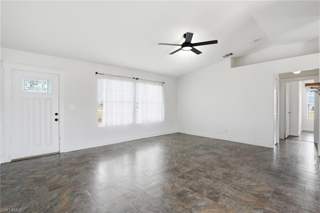 Living area featuring wood-finish flooring, a contemporary ceiling fan, and multiple windows with blinds