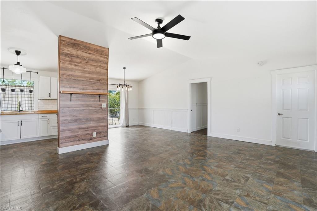 Open-concept living space featuring vaulted ceilings, a contemporary ceiling fan, and tile flooring