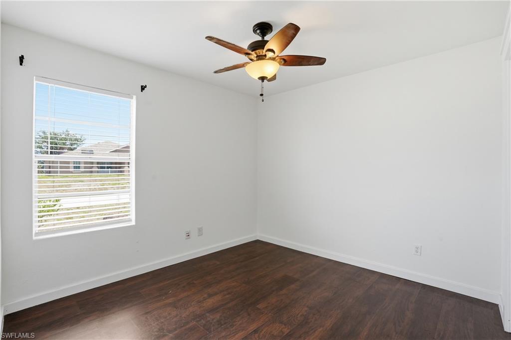 Room featuring wood-finish flooring, white baseboards, and bright white walls