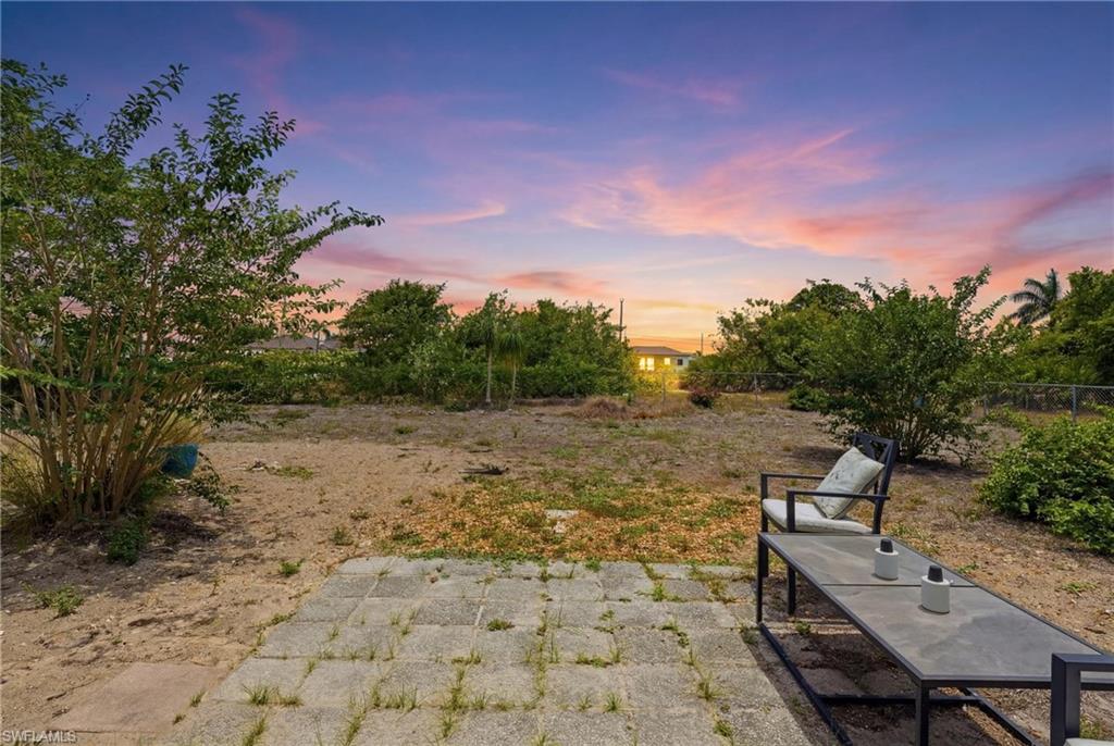 Expansive outdoor space featuring a paver patio and established perimeter plantings
