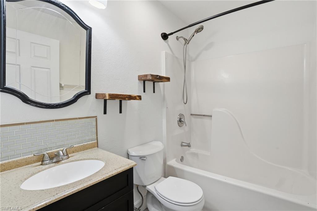 Bathroom featuring a vanity with an oval undermount sink, a light-toned countertop, and a light blue subway tile backsplash