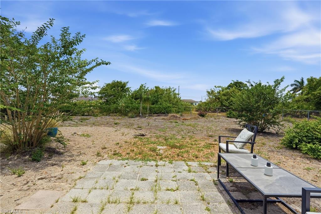 Expansive outdoor space featuring a paved patio area, mature shrubbery, and natural landscaping