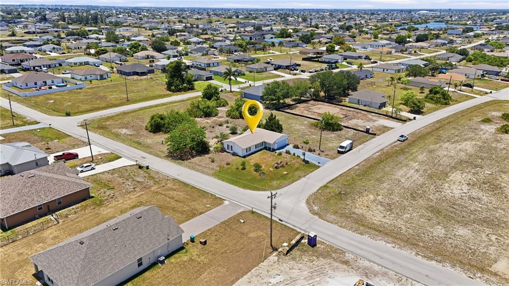 Single-story residence featuring a light-colored exterior and a dark-toned roof situated on a corner lot