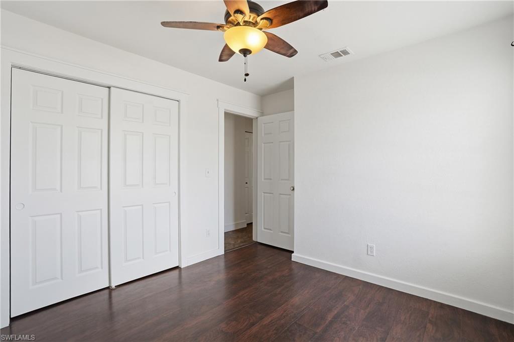 Room featuring wood-finish flooring, a ceiling fan with integrated lighting, and white walls
