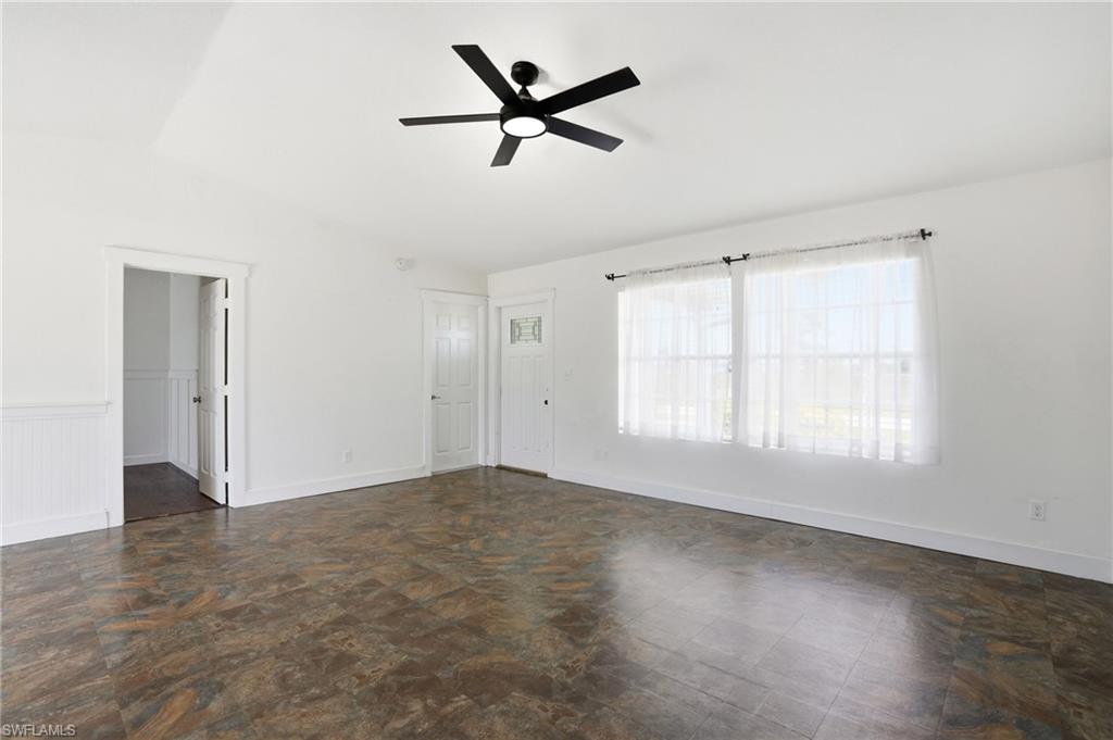 Spacious room featuring patterned tile flooring, a modern black ceiling fan, and white walls