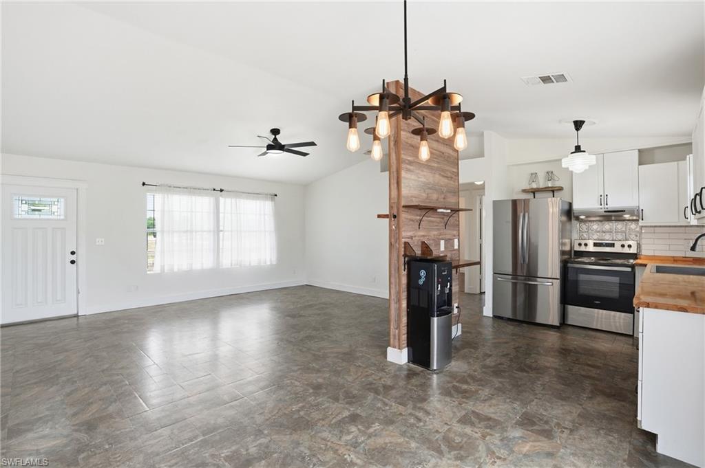 Open-concept living space featuring wood-finish flooring, a contemporary chandelier, and a decorative wood-paneled accent wall