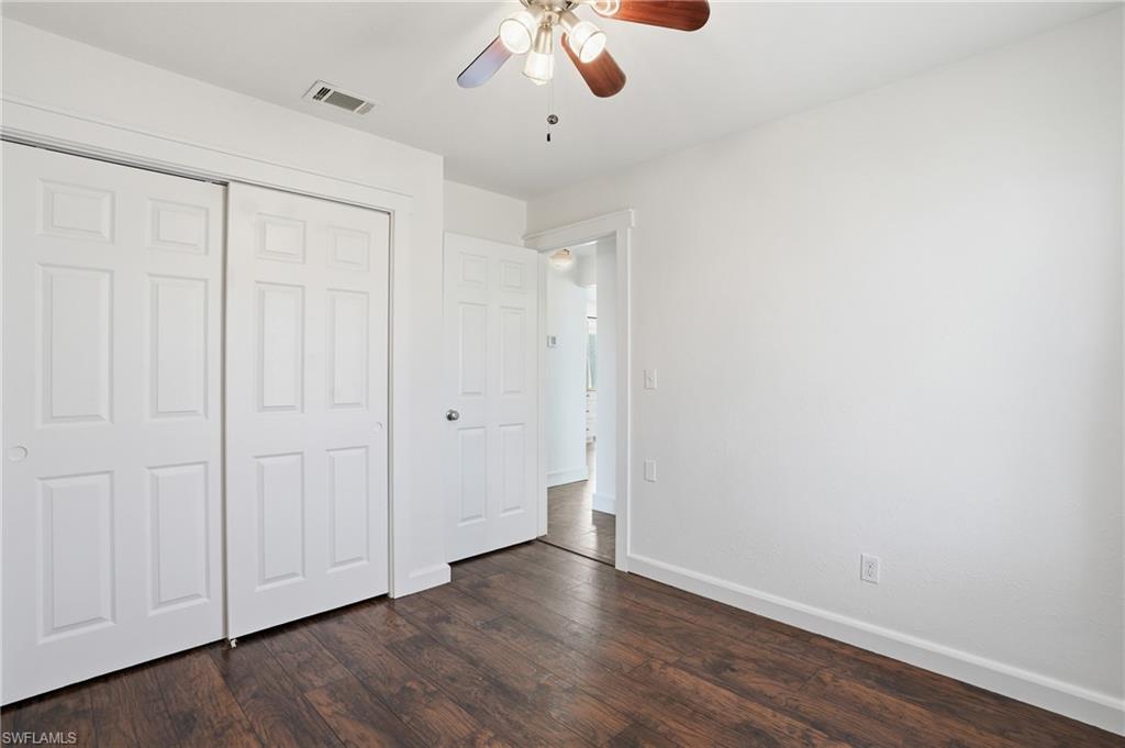 Room featuring wood-finish flooring, white walls, and a ceiling fan with integrated lighting