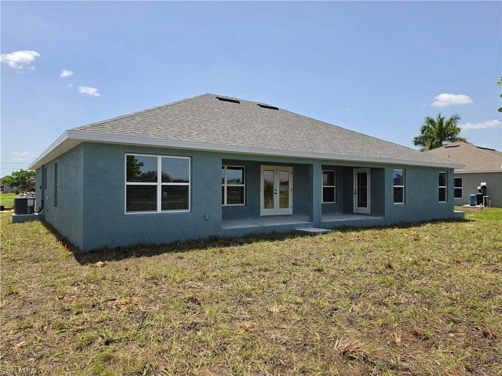 Rear exterior showcasing a covered patio, multiple windows, and a double glass door entry