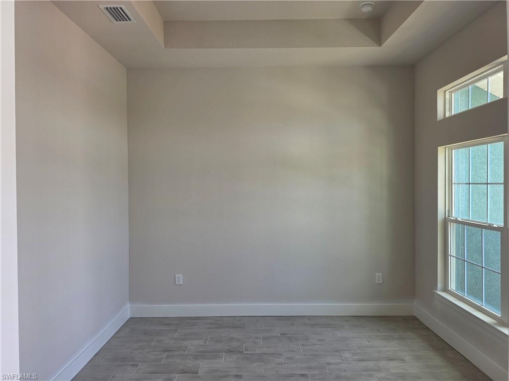 Neutral-toned room featuring a tray ceiling with recessed lighting
