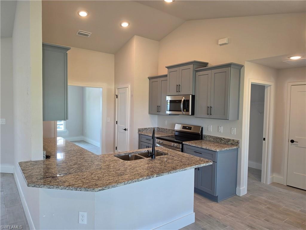 Kitchen featuring a peninsula island with an undermount sink, granite countertops, and gray shaker-style cabinetry