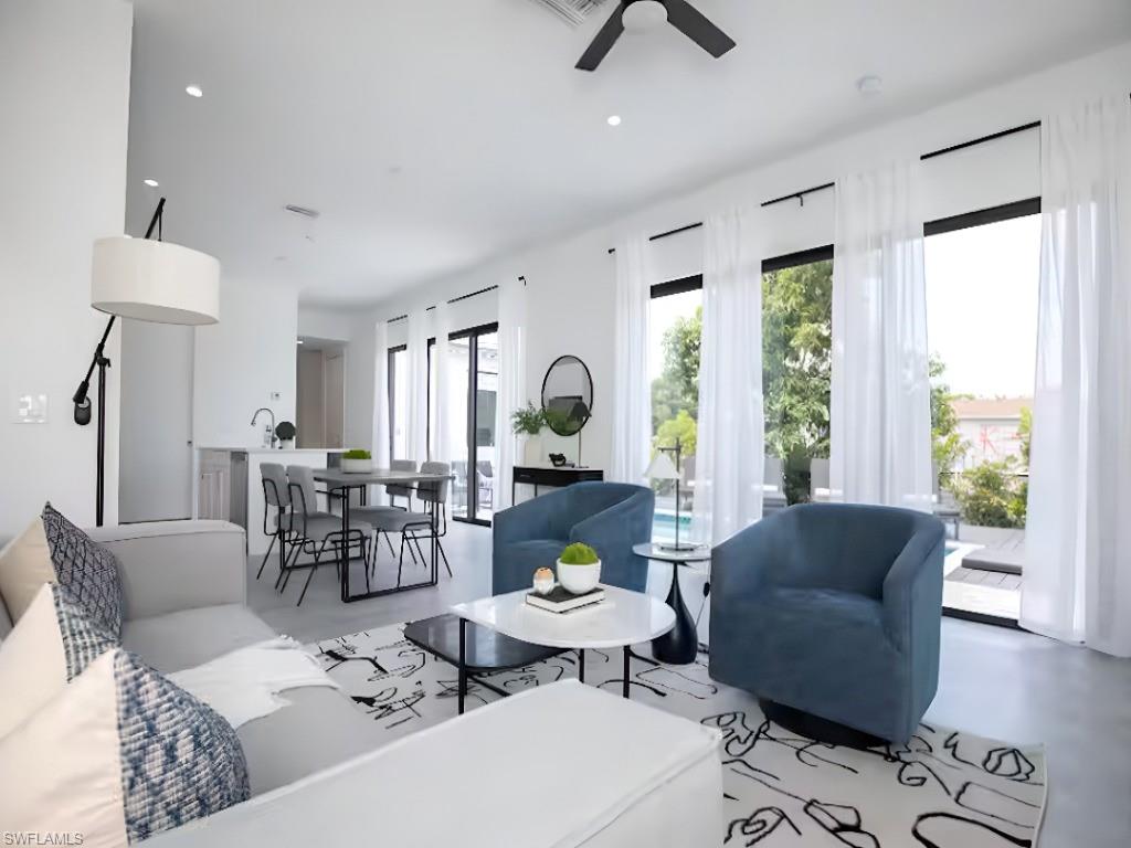 Open-concept living space featuring high ceilings, recessed lighting, and expansive floor-to-ceiling windows with sliding glass door access to the pool