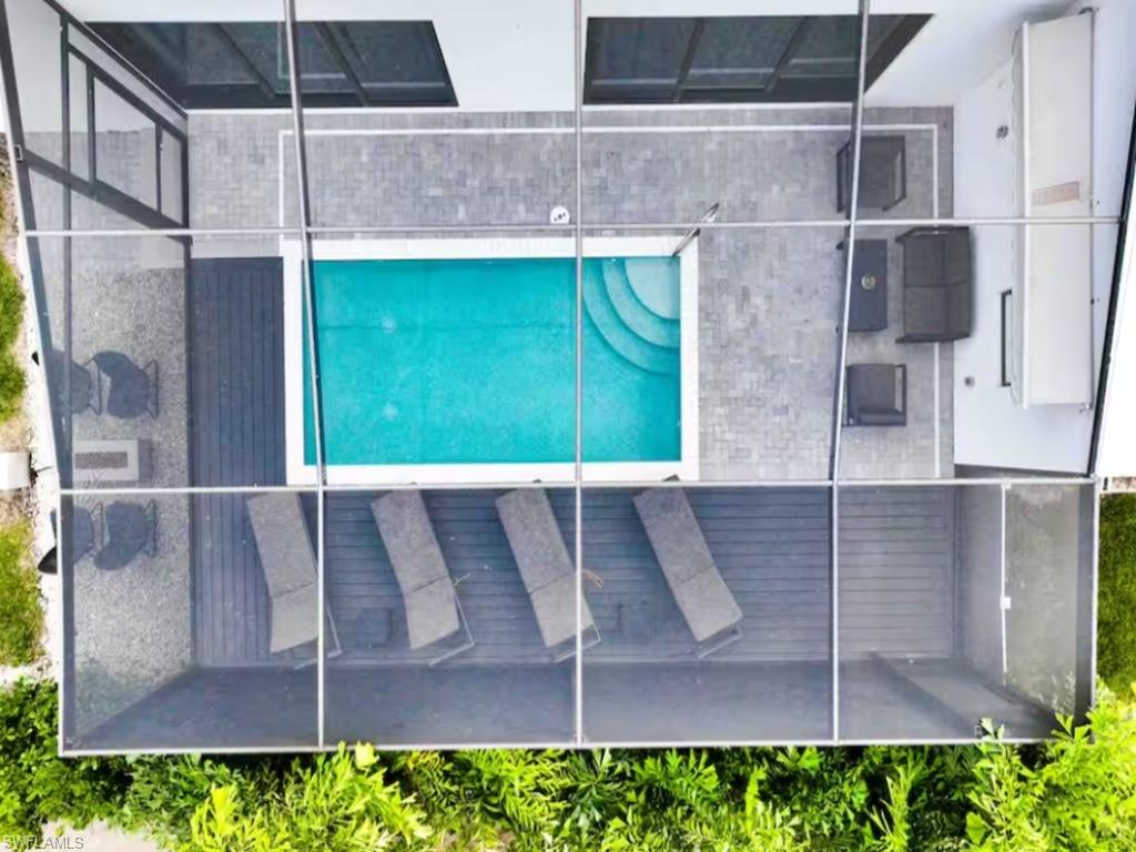 Outdoor screened enclosure featuring a rectangular pool with steps, a paver deck, and composite decking