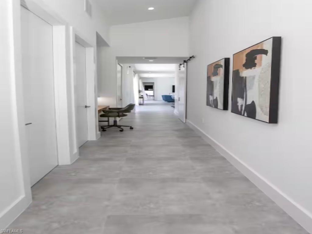 Long hallway with light gray tile flooring, crisp white walls, and contemporary recessed lighting