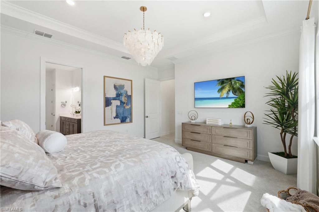 Primary Bedroom Suite featuring tray ceiling, Chandelier and pendant lighting