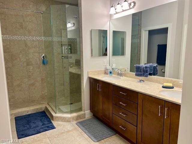 Bathroom featuring a shower with door, tile flooring, and double sink vanity