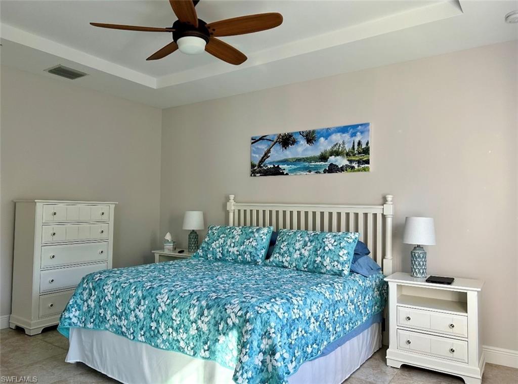 Bedroom featuring tile floors, ceiling fan, and a tray ceiling