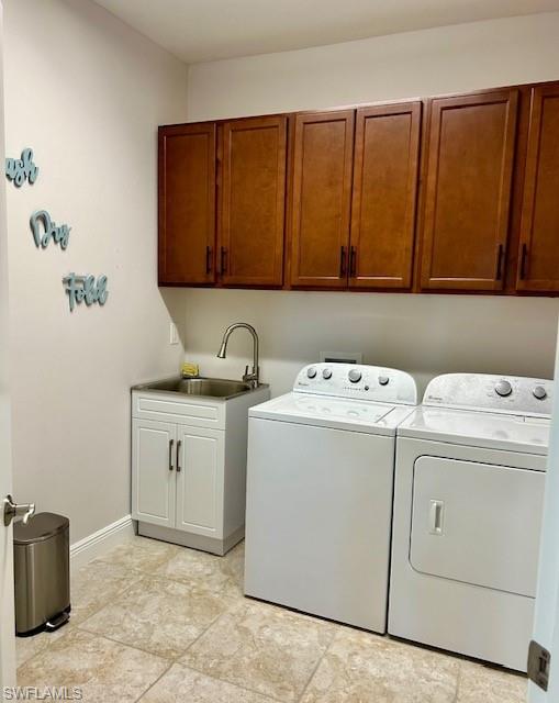 Clothes washing area with independent washer and dryer, sink, light tile floors, and cabinets