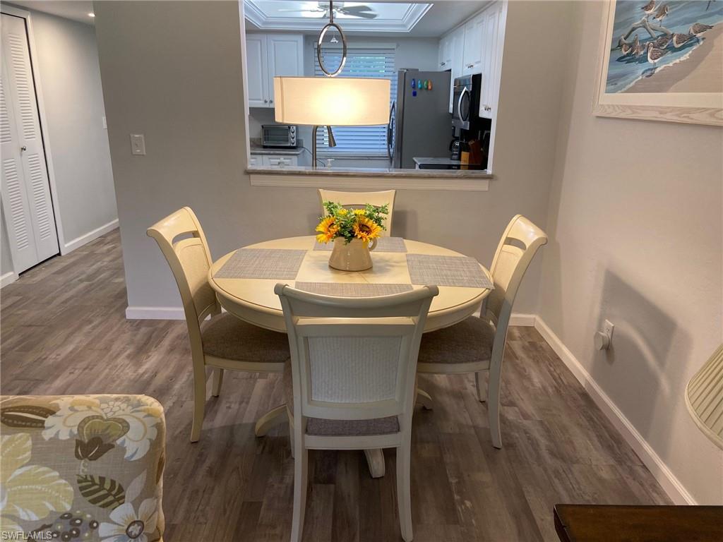 Dining area with wood-type flooring, ornamental molding, and a raised ceiling