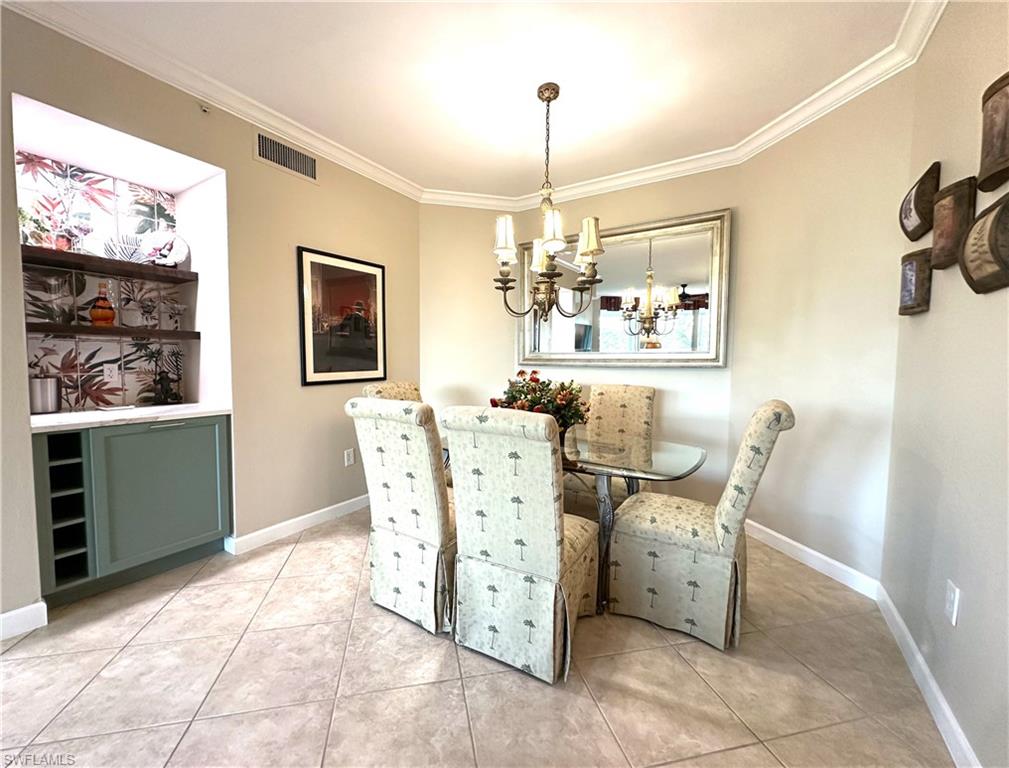 Tiled dining room featuring ornamental molding and a chandelier