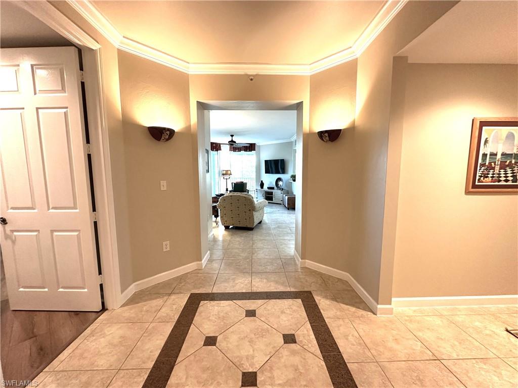 Hallway featuring ornamental molding and light tile floors