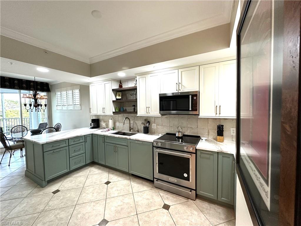 Kitchen with tasteful backsplash, crown molding, white cabinets, sink, and appliances with stainless steel finishes