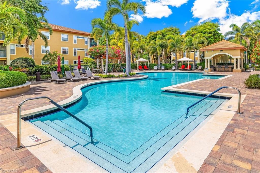 Beautiful resort-style swimming pool featuring a curved design, integrated steps, and surrounding paver decking