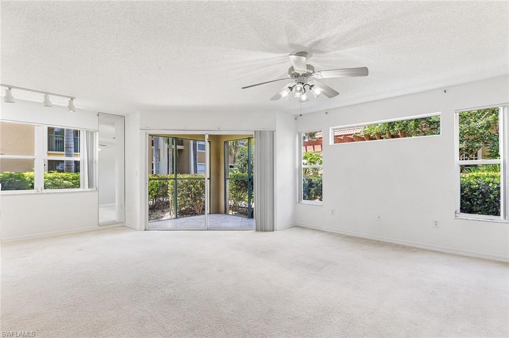 Spacious living area featuring light-colored carpeting and white walls, and slider door to the screened lanai area.