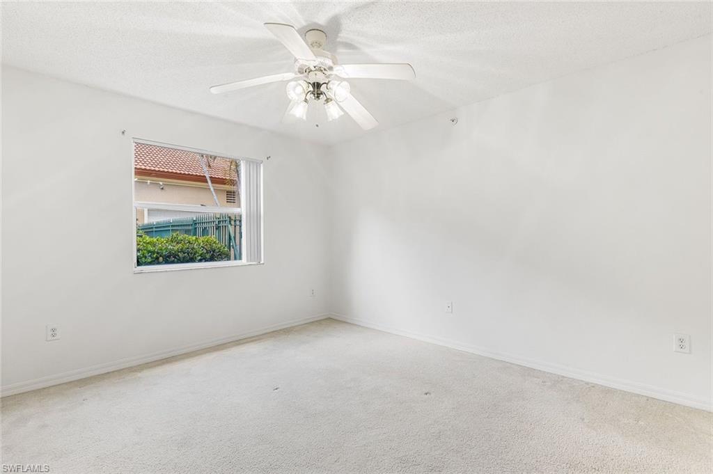 Bedroom with neutral wall colors, carpet flooring, ceiling fan, and large walk-in closet.