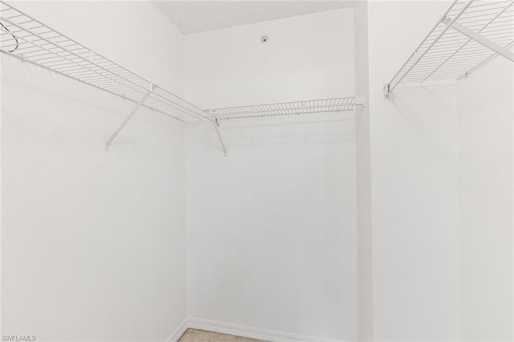 Large walk-in closet featuring white wire shelving and hanging rods