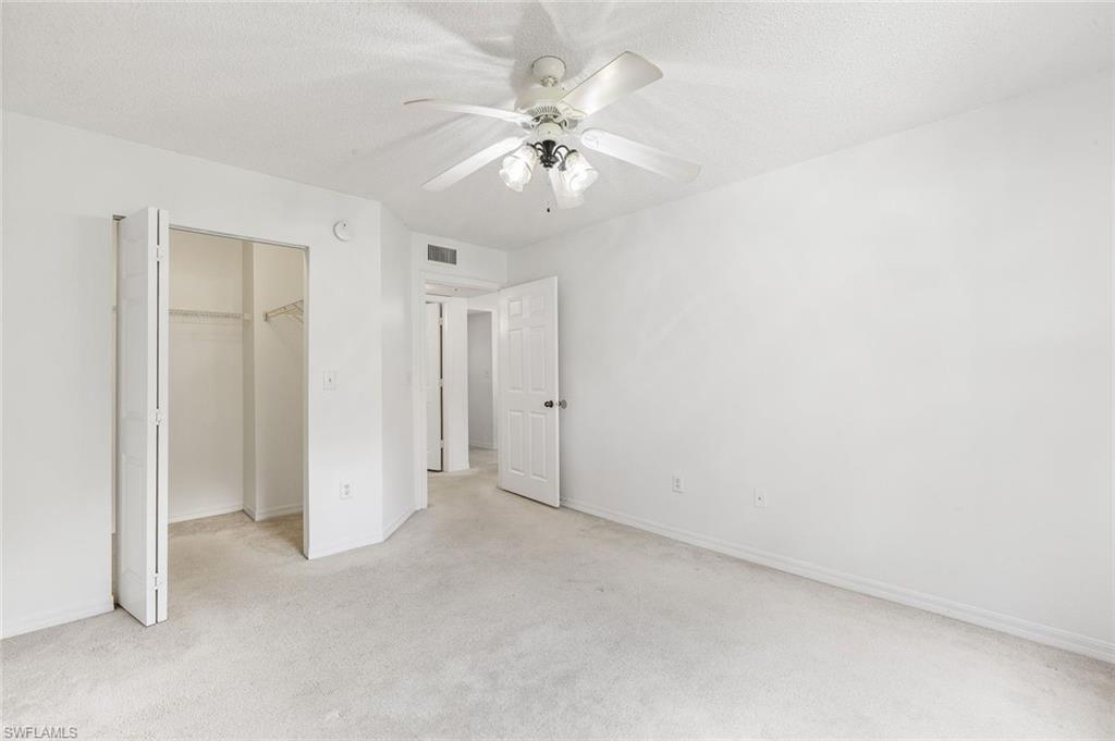 Carpeted interior space featuring a ceiling fan with integrated lighting, bi-fold closet doors, and white painted walls and trim, and large walk-in closet.