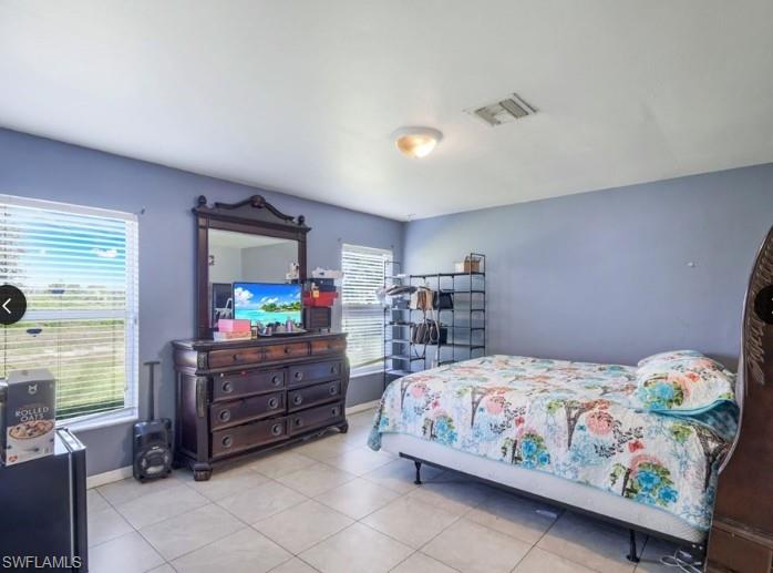 Spacious room featuring tile flooring, two windows with horizontal blinds, and a flush mount ceiling light fixture