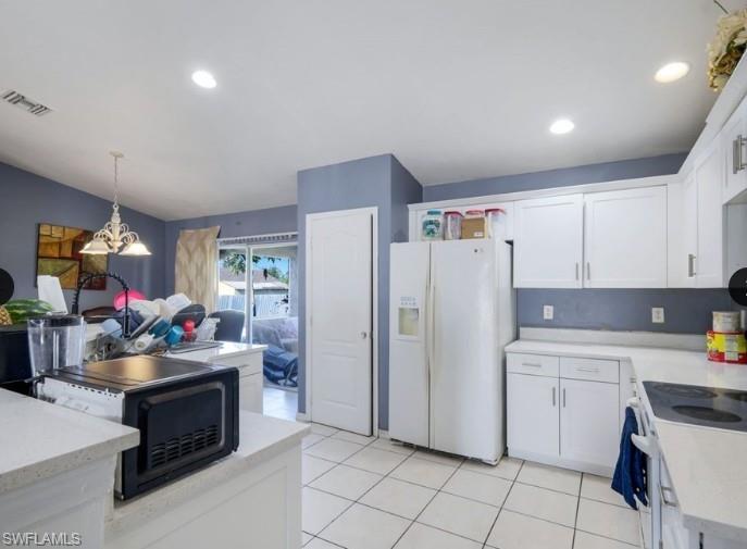Kitchen featuring white cabinetry, light countertops, white tile flooring, recessed lighting, and a sliding glass door to an outdoor area