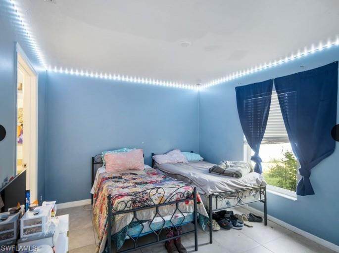 Room featuring light blue walls, recessed ceiling lighting, a window with horizontal blinds, and tile flooring