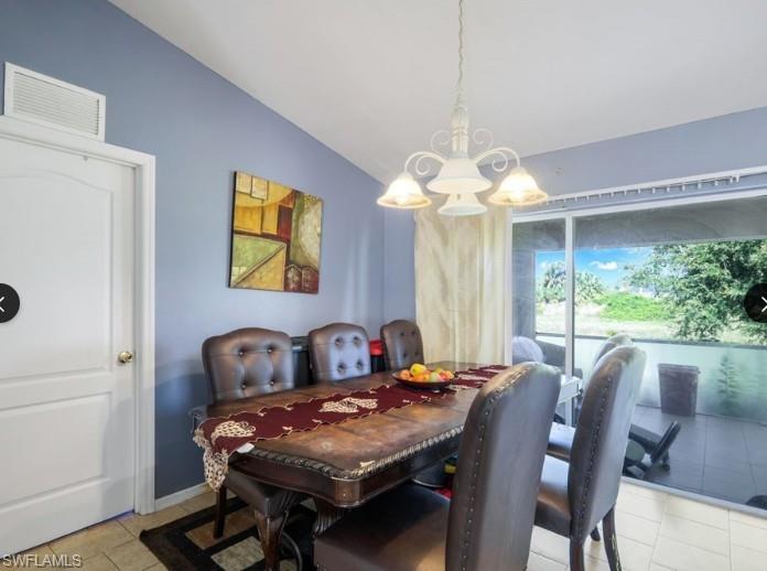 Dining area featuring vaulted ceilings, a decorative white chandelier, ceramic tile flooring, and sliding glass doors opening to a screened patio