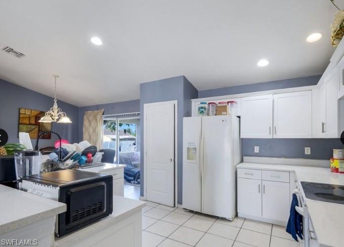 Kitchen featuring white cabinetry, light-colored countertops, and white tile flooring
