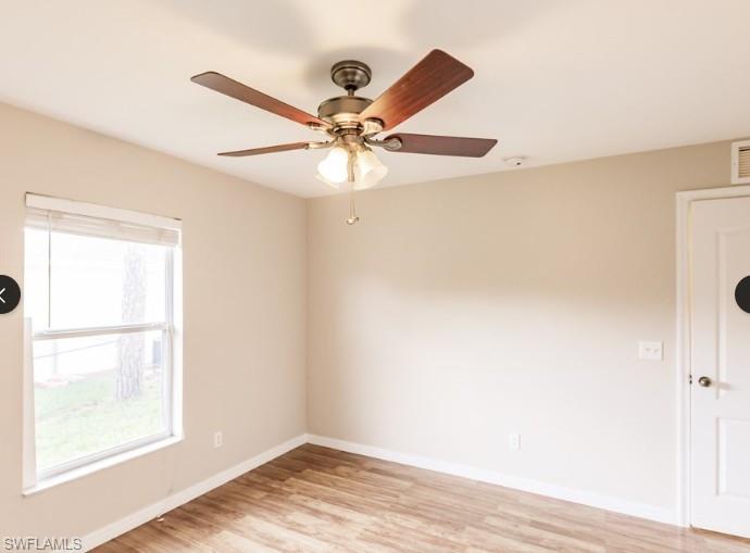 Room featuring wood-finish flooring, a ceiling fan with integrated lighting, a double-hung window with blinds, and neutral wall tones