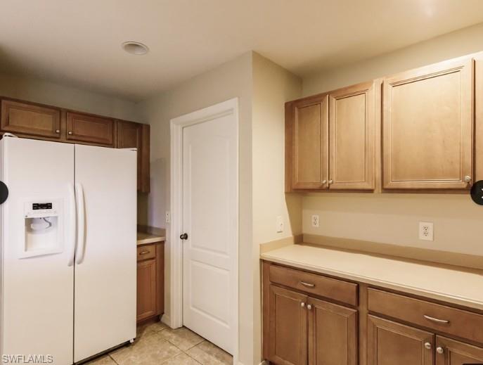Kitchen featuring wood-finish cabinetry, solid surface countertops, and tile flooring
