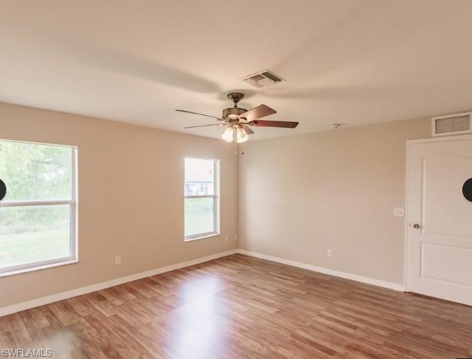 Spacious room featuring wood-finish flooring and two windows providing natural illumination