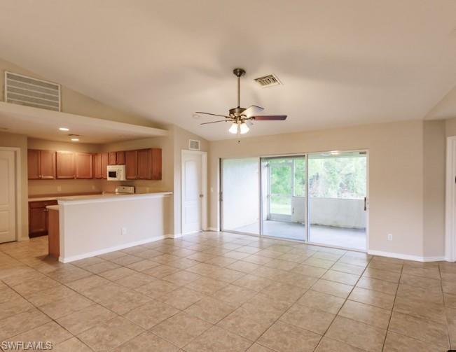 Spacious open-concept living area featuring tile flooring, vaulted ceilings, and a ceiling fan