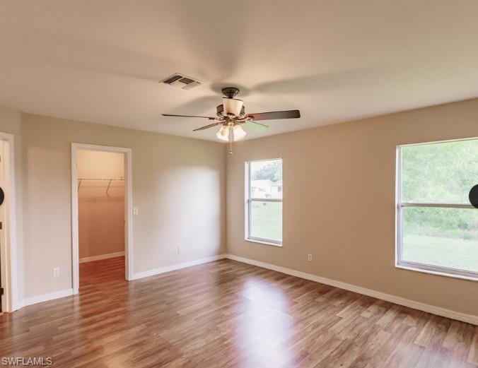 Spacious room featuring wood-finish flooring, neutral-toned walls, and white baseboards