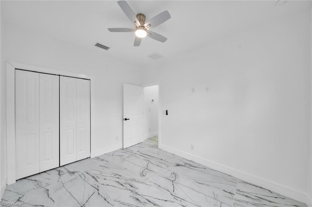 Spacious interior room featuring white walls and a contemporary ceiling fan