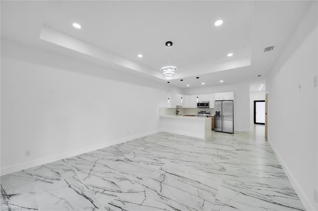 Open-concept living space featuring high ceilings with recessed lighting, white walls, and large format marble-look flooring