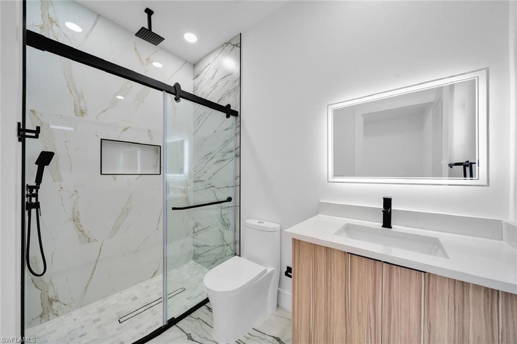Modern bathroom featuring a glass-enclosed shower with matte black hardware, a rainfall showerhead, and a recessed niche