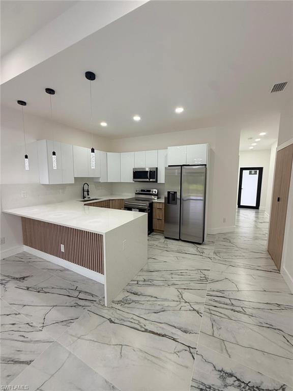 Contemporary kitchen with a large central island featuring a slatted wood-look panel accent, white countertops, and modern pendant lighting