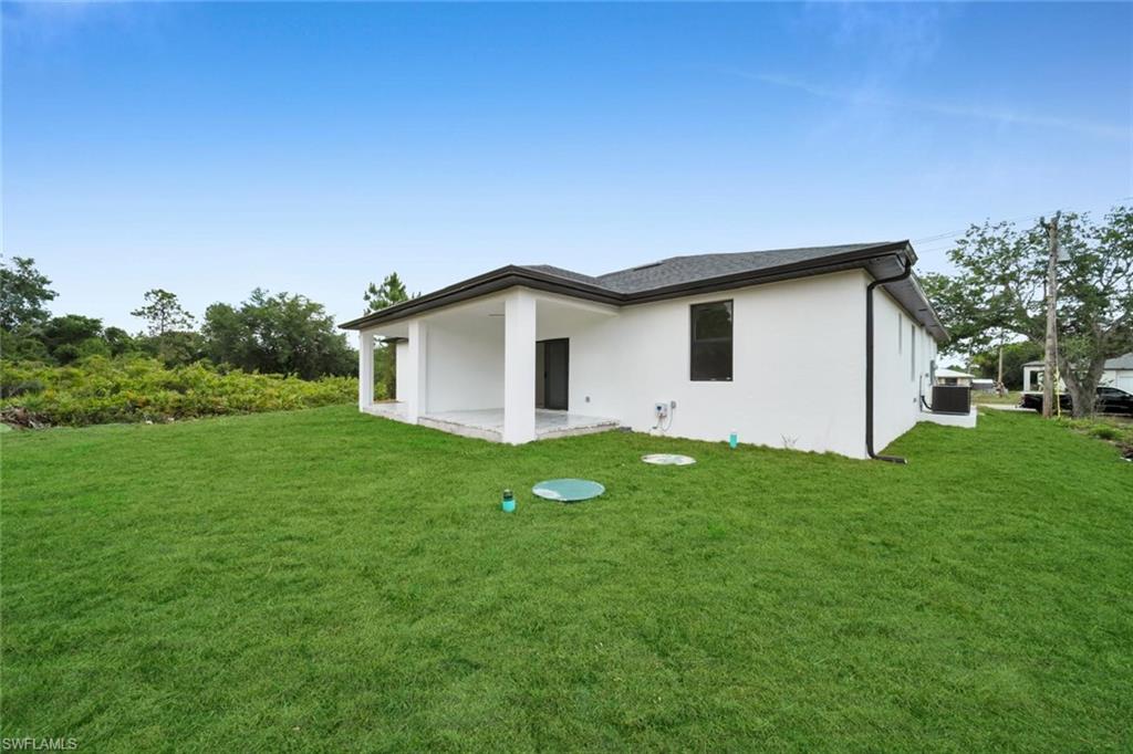 Expansive green lawn with a white stucco exterior and dark shingle roof